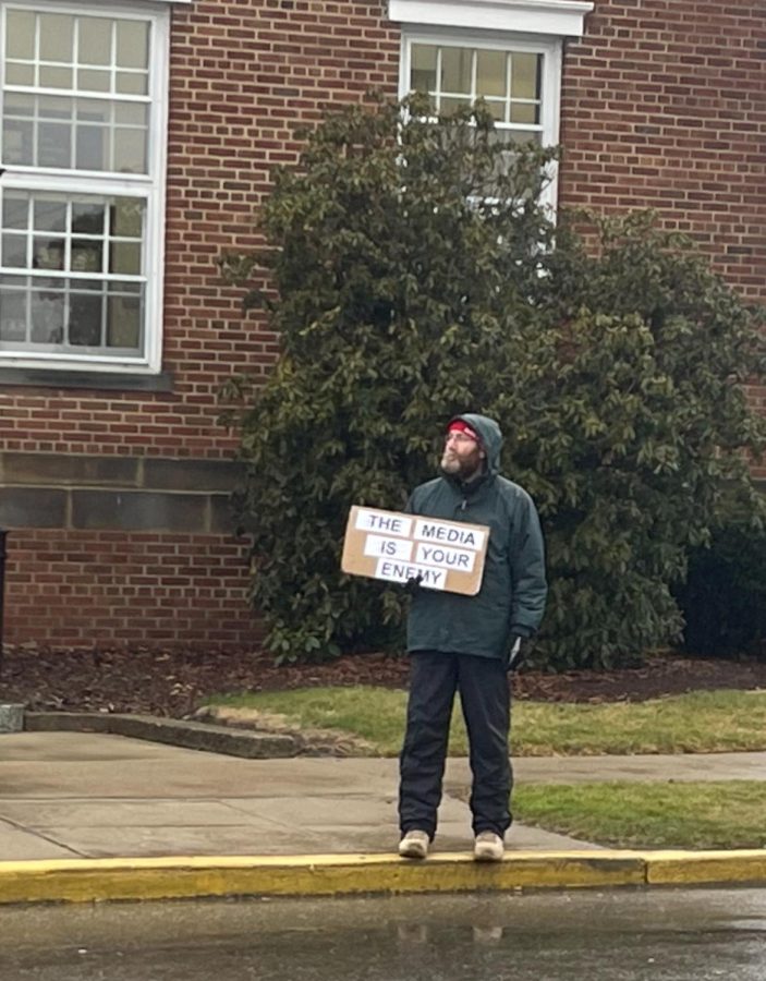 A man holds a sign that reads, "The media is your enemy," on North Market Street in East Palestine Feb. 22. East Palestine residents and visitors stood outside waiting for former president Donald Trump and Donald Trump Jr. to arrive.