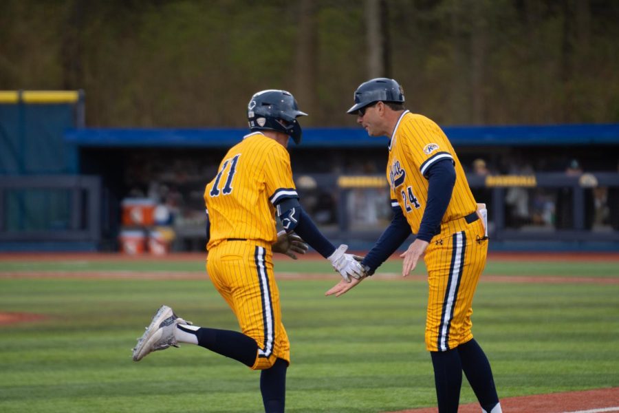 Freshman Kolton Schaller is congratulated by coach Jeff Duncan as he passes third base April 30, 2023. 