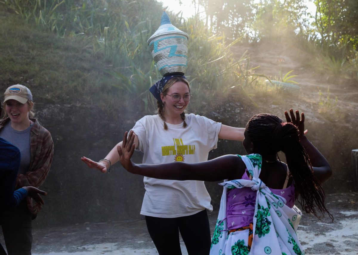 Lily Keister, Kent State higher education master’s student, balances a basket on her head while participating in cultural dance at Twin Lakes, Rwanda.