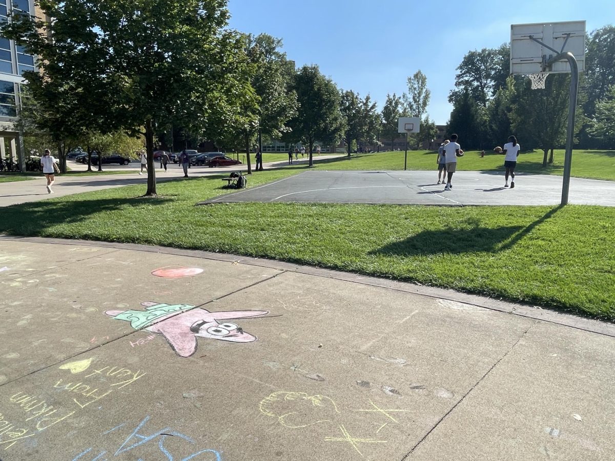 Students play basketball by Tri Towers as they enjoy the warm weather, while the remnants of the Kent Navs chalk art competition is on the ground. 