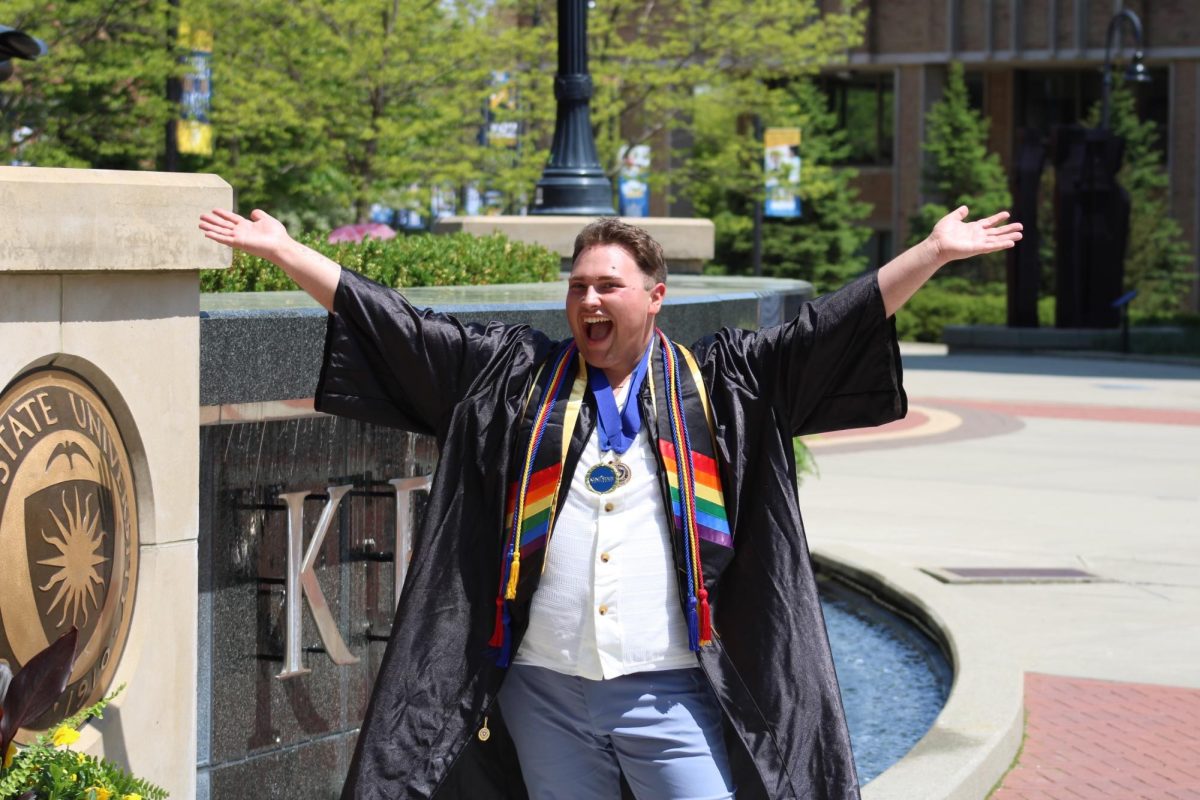 Gavin Aitken celebrates his graduation while standing in front of the Kent State University fountain sign in May 2023. He now works as a graduate teaching assistant the University of Tennessee's Jones Center for Leadership and Service.