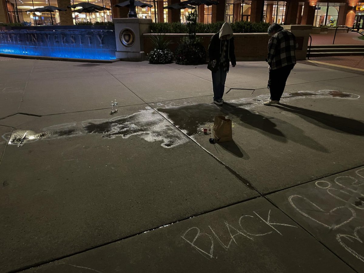 Kent State students erase chalk writing on the K speaking out against voting "Yes" on Issue 1 with bottles of water on Oct. 18, 2023.