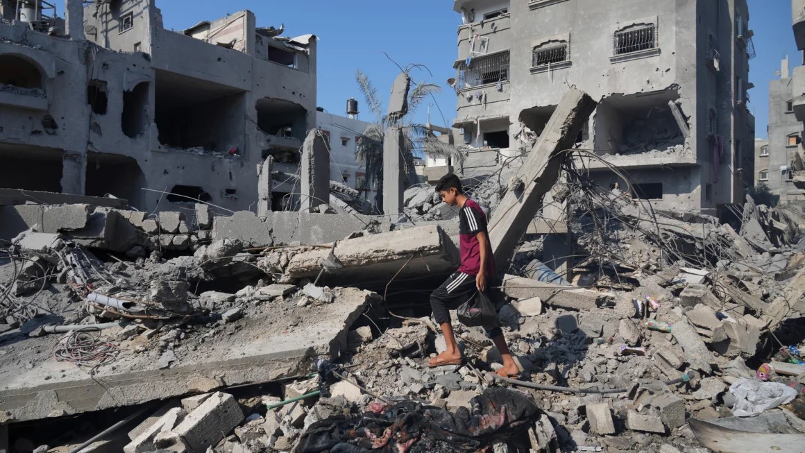 Palestinians stand by buildings destroyed in Israeli airstrikes in Deir al-Balah, Saturday, Oct. 14, 2023. Amnesty's report focused on two strikes in this neighborhood.