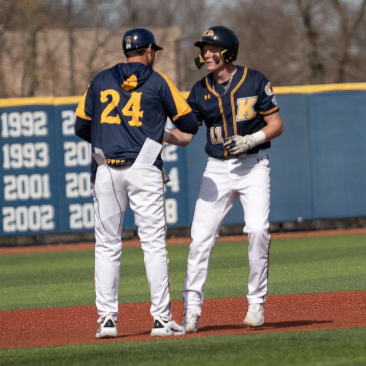 Coach Jeff Duncan (left) confers with Kolton Schaller following Schaller's double in the second inning of the Golden Flashes' 27-0 blowout of Youngstown State on March 12, 2024.