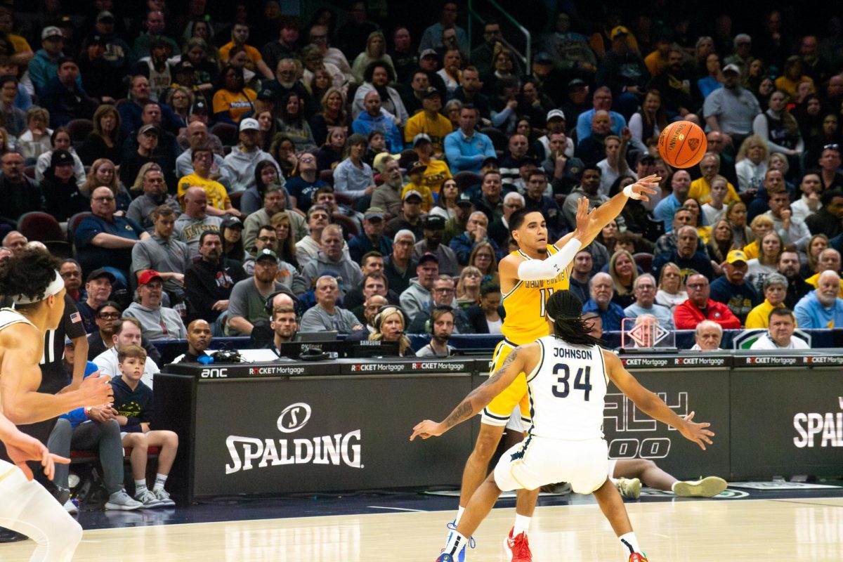 Kent State redshirt senior Giovanni Santiago passes the ball off as Akron redshirt sophomore Nate Johnson guards him in the MAC Men's Basketball championship tournament game on Saturday, March 16, 2024. 