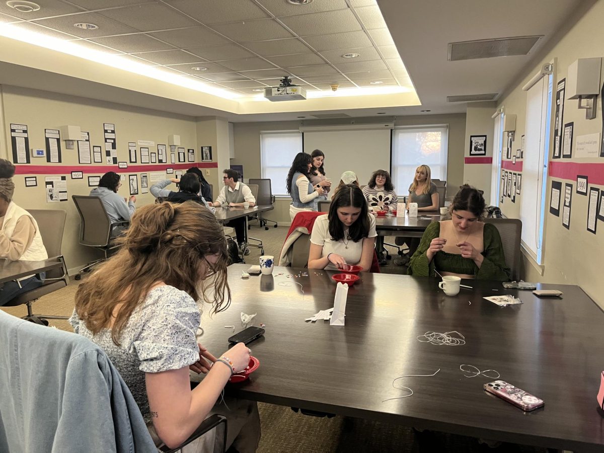 Attendees at URGE's feminist tea party sort through beads while making. bracelets on March 11, 2024.