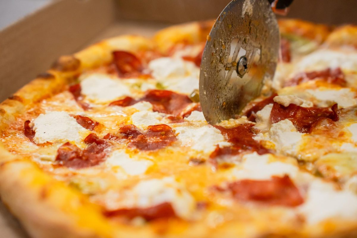 A worker at Lucci's Place slices a pizza fresh from the oven. 