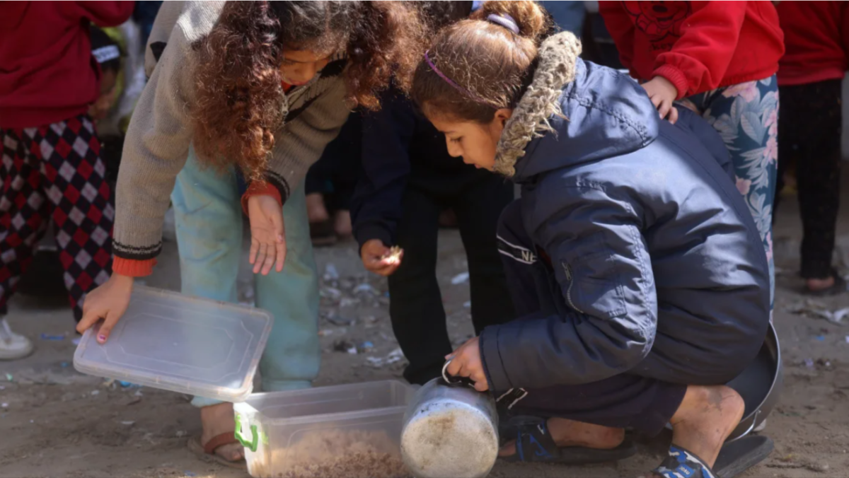 Displaced Palestinian children prepare to have a meal of rice near a food distribution point in Rafah in the southern Gaza Strip, amid the ongoing conflict between Israel and Hamas militants. 