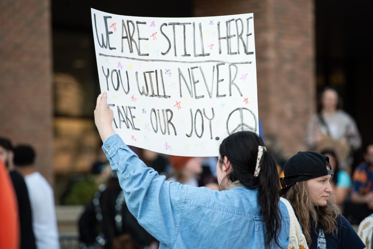 A protester bearing a sign joins a crowd gathered on the K to protest Kyle Rittenhouse's speech April 16, 2024.