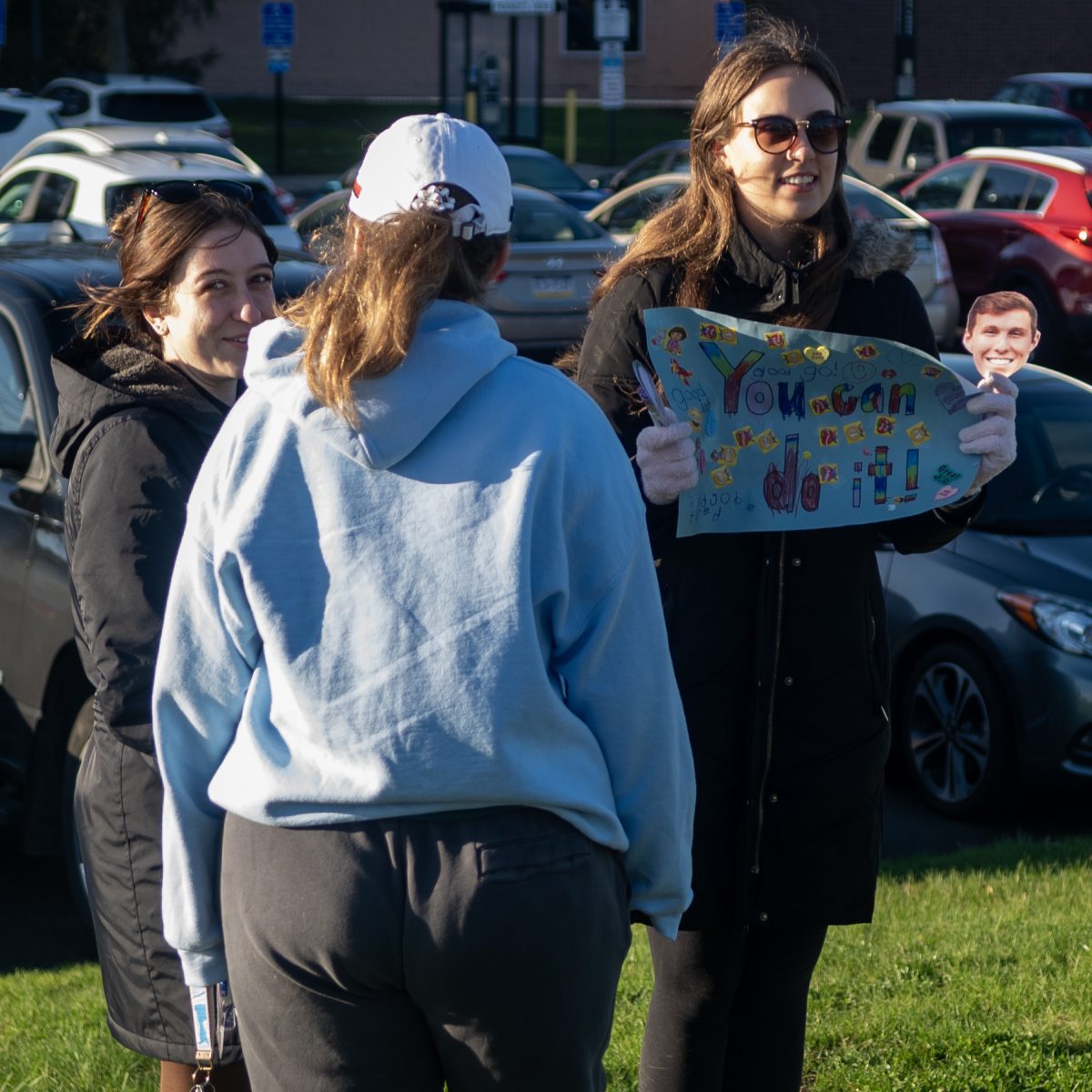 Courtney Kennedy, right, cheers on runners with friends Kelsey Nist, left, and Meaghan Buckholdt at the Black Squirrel 5k on April 13, 2024.