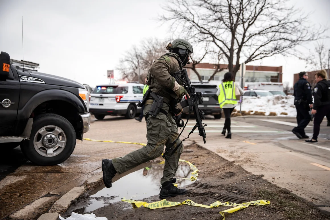 A SWAT team member runs toward the supermarket where a gunman opened fire