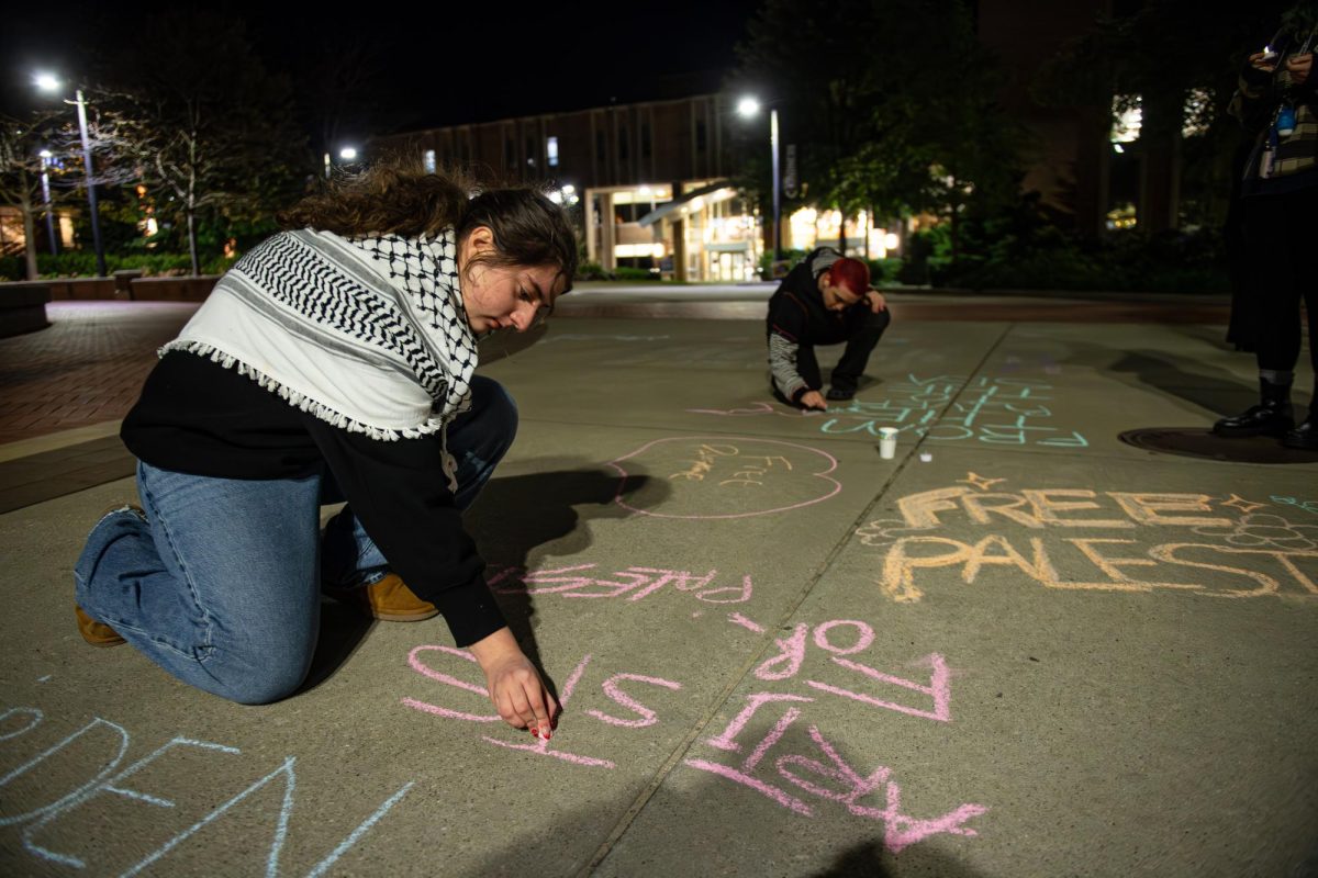 Kent freshman Sarah Rizk chalkes messages on Riseman Plaza after the conclusion of the candlelight vigil, Thursday, Oct. 11, 2024. Half Palestinian in descent, Rizk attended the event to be a voice for her ancestors and help support the cause.