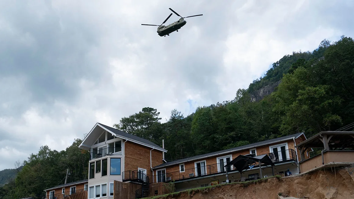 A helicopter flies above a damaged structure in Chimney Rock, North Carolina, on October 2, 2024.