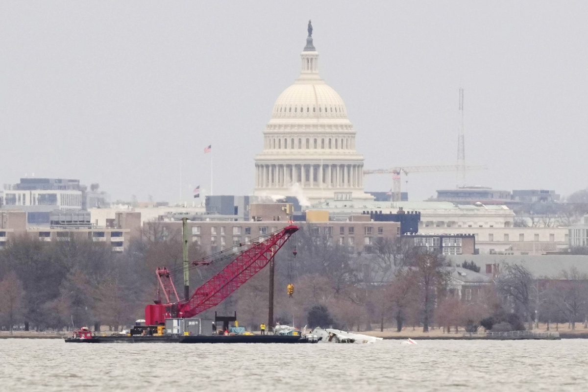 With the US Capitol in the background, a crane sits in the Potomac River on Sunday. It will be used by salvage teams this week to remove large pieces of the wreckage of American Airlines Flight 5342.