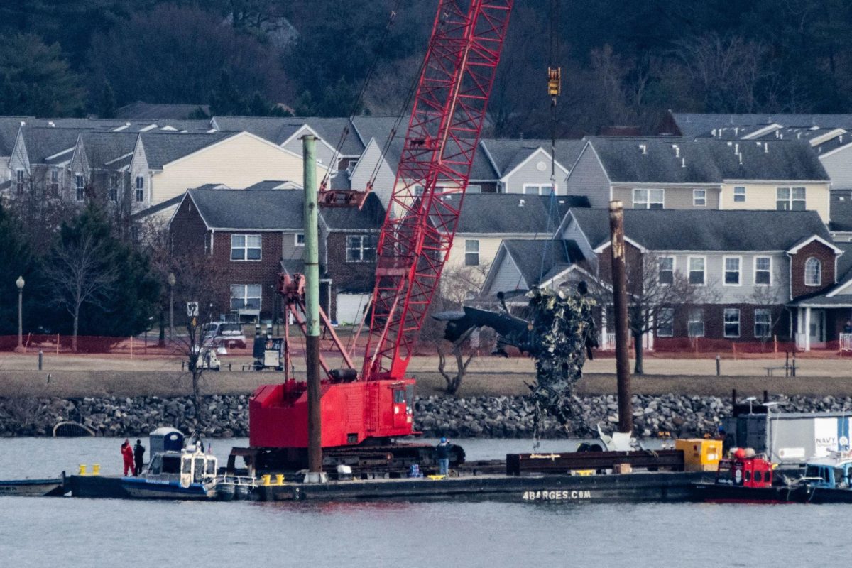 Recovery teams lift the mangled remains of a military helicopter that crashed midair with an American Airlines commercial airplane from the Potomac River.