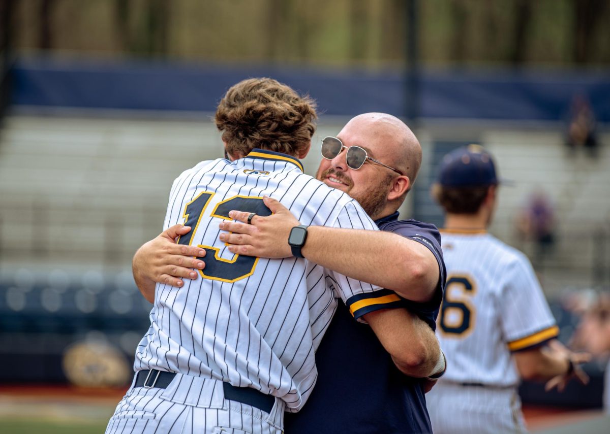 Athletic trainer Evan Schreyer hugs redshirt freshman Landon Tiesing on Friday, April 25, 2025.