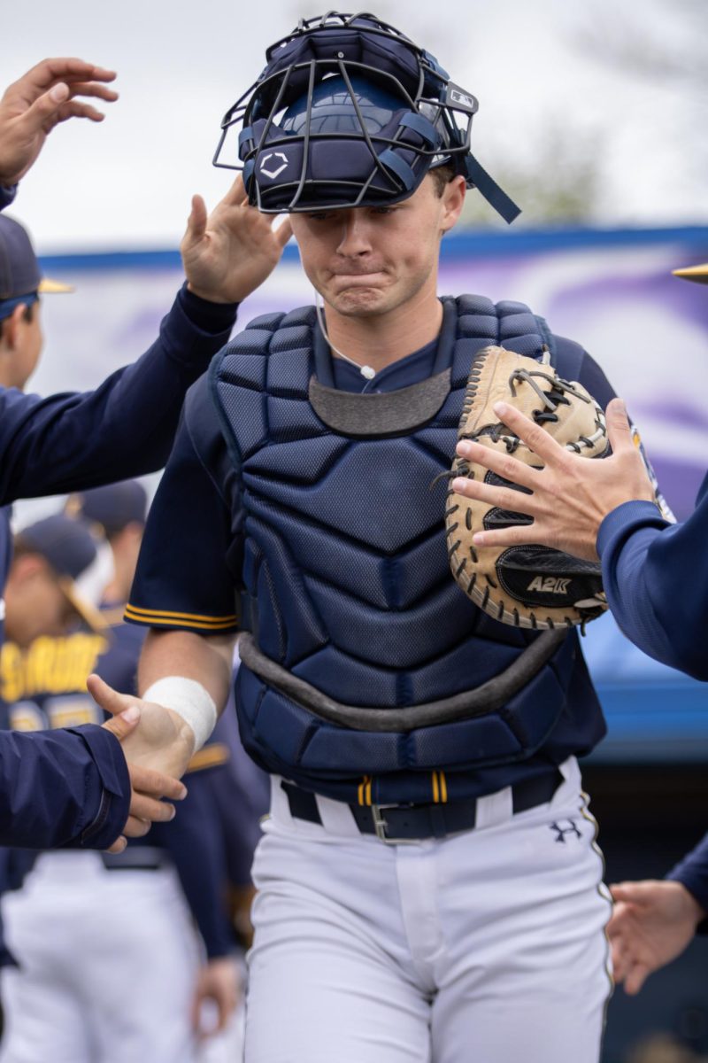 Kent junior Brody Williams walks through the tunnel as his teammates cheer him on before their game against Akron on Saturday, April 26, 2025. 