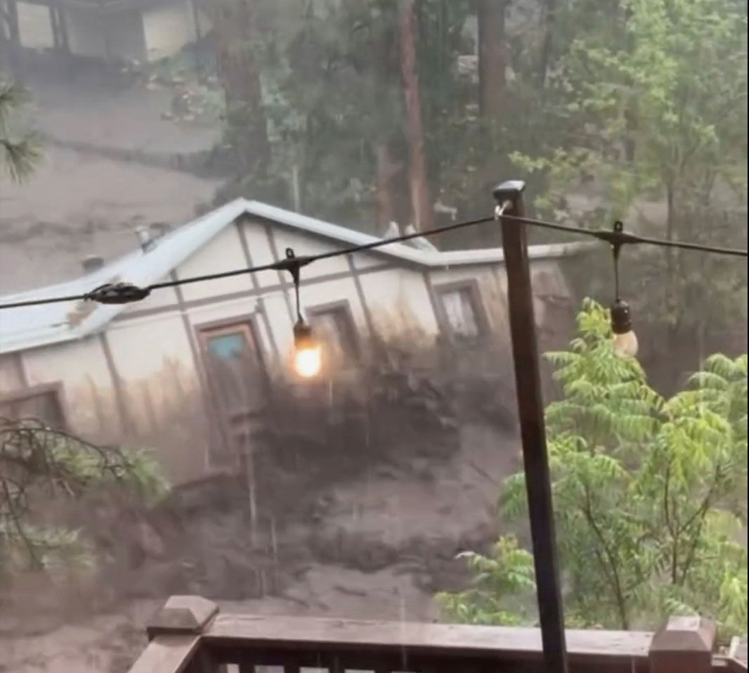 In this image taken from video, a house is carried away by flash flooding behind a house in Ruidoso, New Mexcio, on Tuesday.