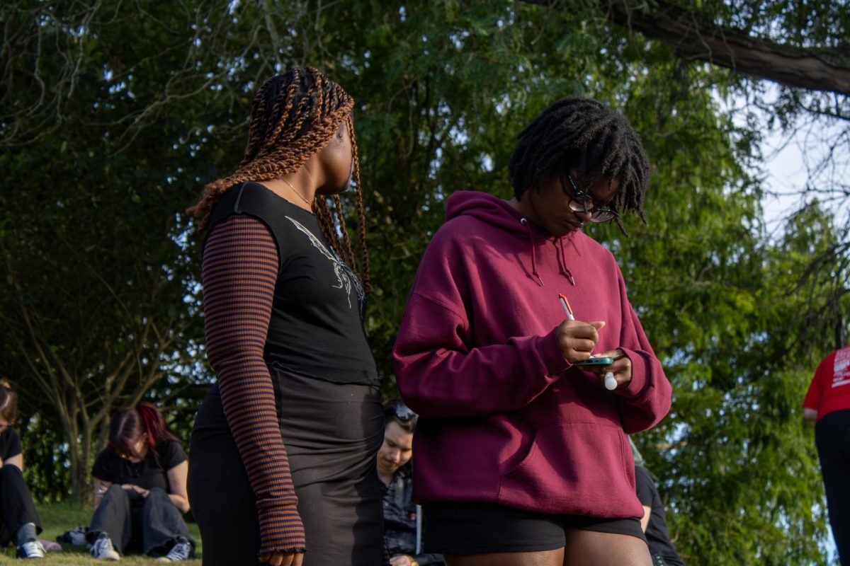 Kent senior Toni Harper, Visual Communication Design major, writes down her thoughts on how the centers were important to her as her sister, Cori Harper, Kent senior visual communication design major watches her after the march on Wednesday, August 27th, 2025. 
