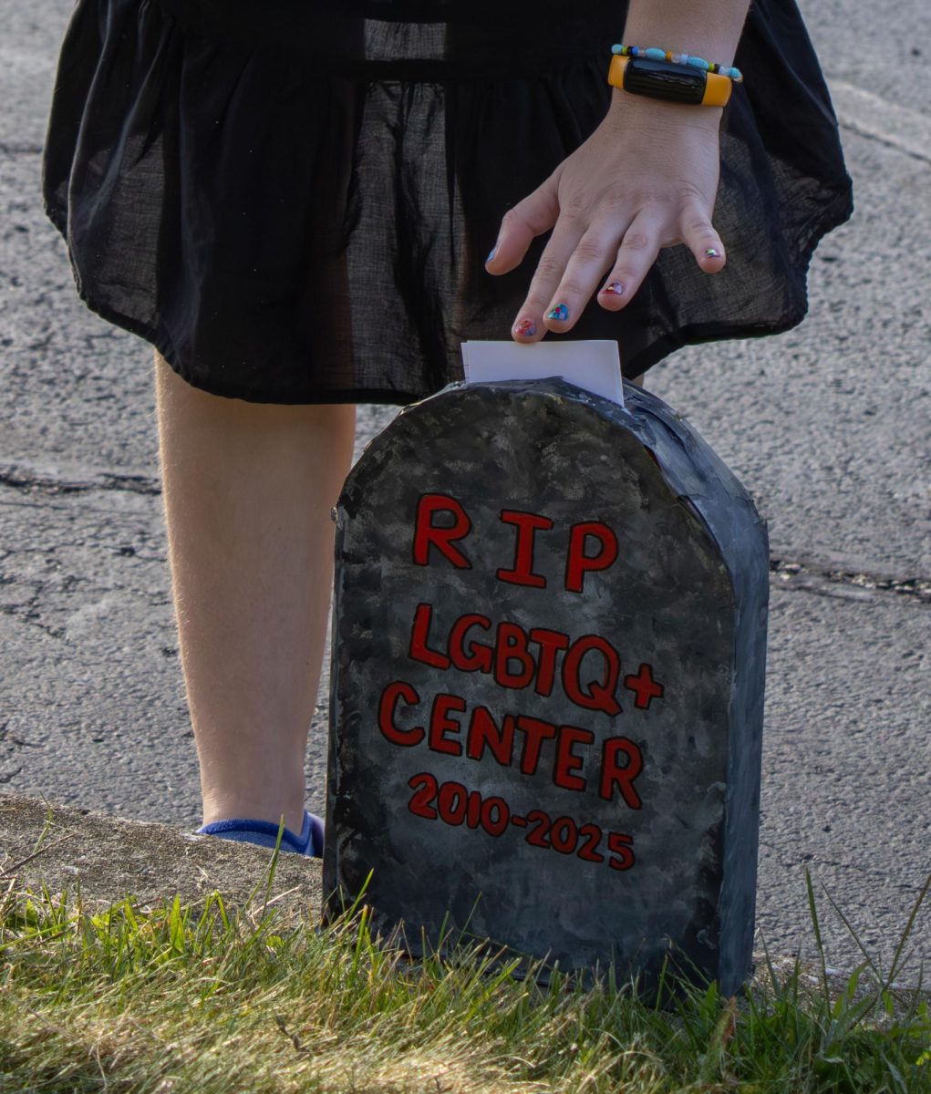 Kent junior Jamie Vesely, an early childhood education major, puts their notecard in the gravestone box that is labeled "R.I.P LGBTQ+ Center 2010-2025" during the "We Wear Black" protest on Wednesday, August 27, 2025. The Ohio Student Association passed out notecards to protesters to write about how the Women's center, Multicultural Center, and the LGBTQ+ center was important to them. 