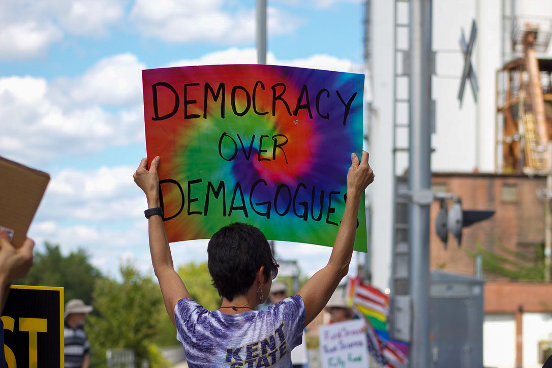 Julie Sykes, 61, holds up a sign reading "Democracy Over Demagogues" during the 'Workers Over Billionaires' protest located at the Kent gazebo on Monday, Sept. 1, 2025. Attendees could be heard chanting and ringing instruments.