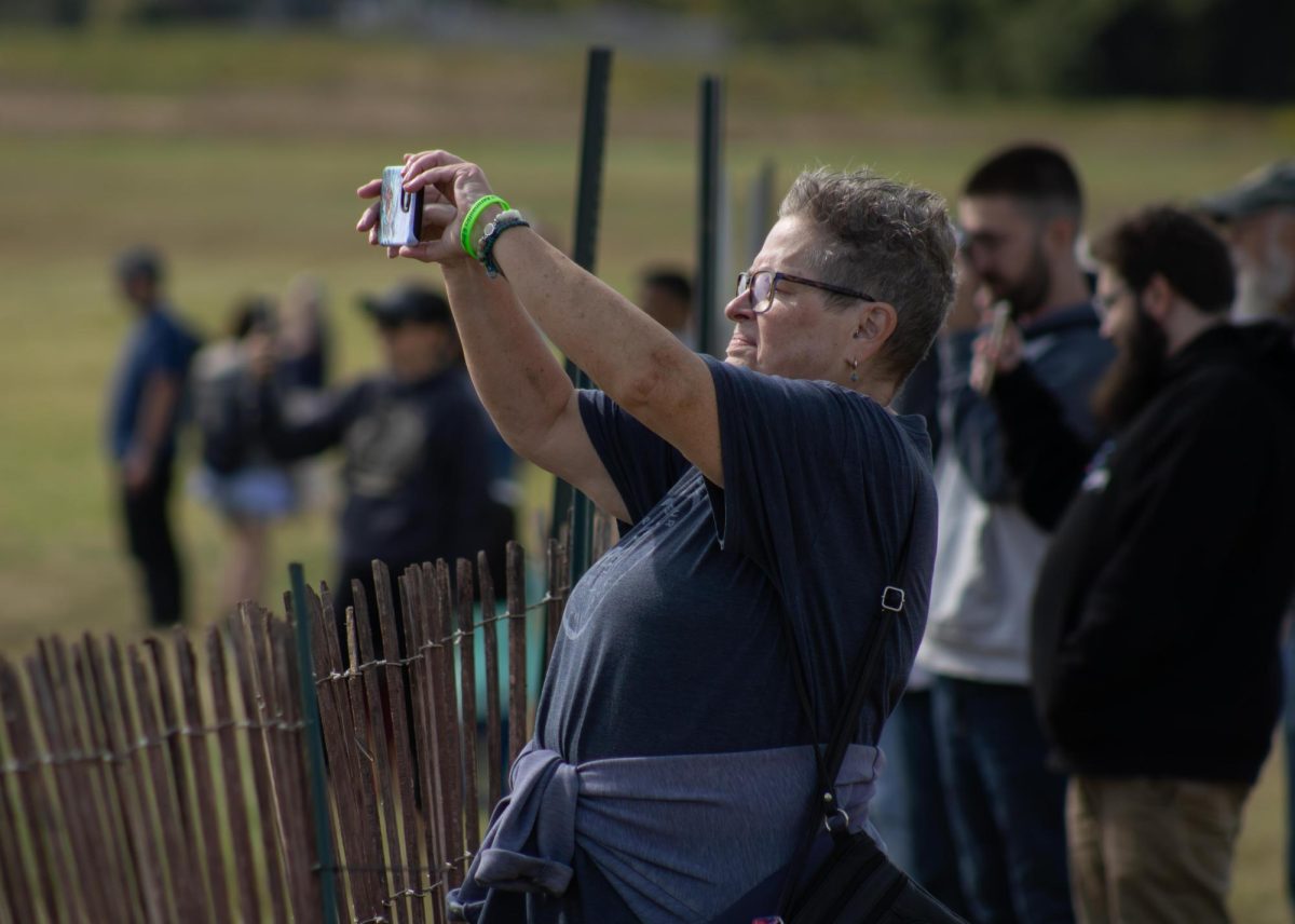 Pam May, resident in Stow, records the Goodyear Blimp flying around the Kent State Airport during the Aeronautics and Engineering expo on Saturday, Sept 6, 2025. She has been attended the expo every year since her son became a student and graduated at Kent in 2017.