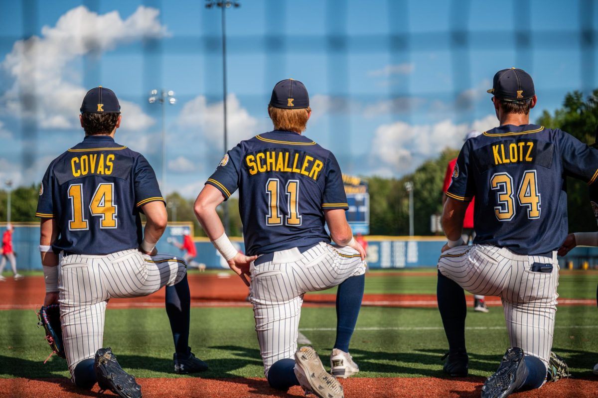 From left to right: Kent junior Alejandro Covas, senior Kolton Schaller, and Graduate student Hunter Klotz takes a knee while Malone warms up before their game on Sept. 26, 2025.