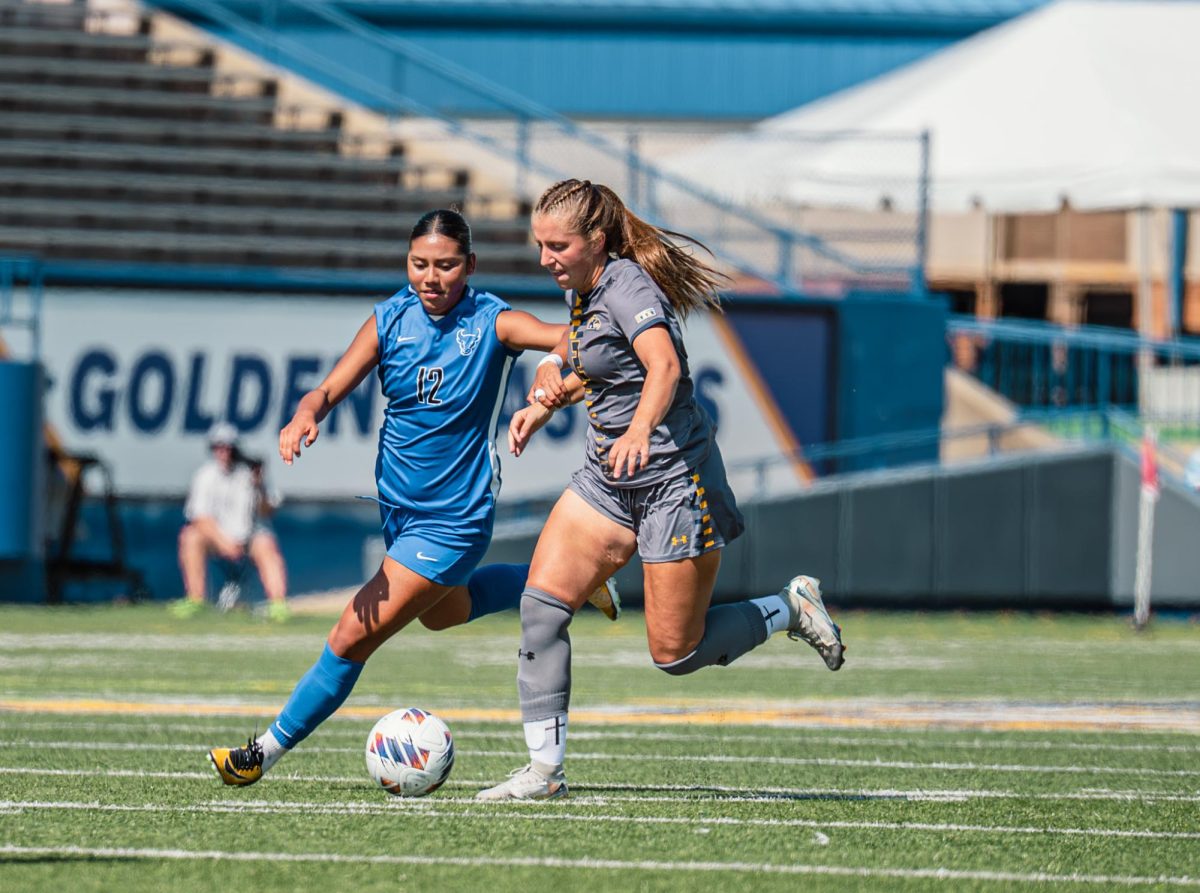 Kent junior Samantha Miller runs upfield while Buffalo senior Ashley Reyes defends her in the first half of the game on Sunday, Sept. 28, 2025.