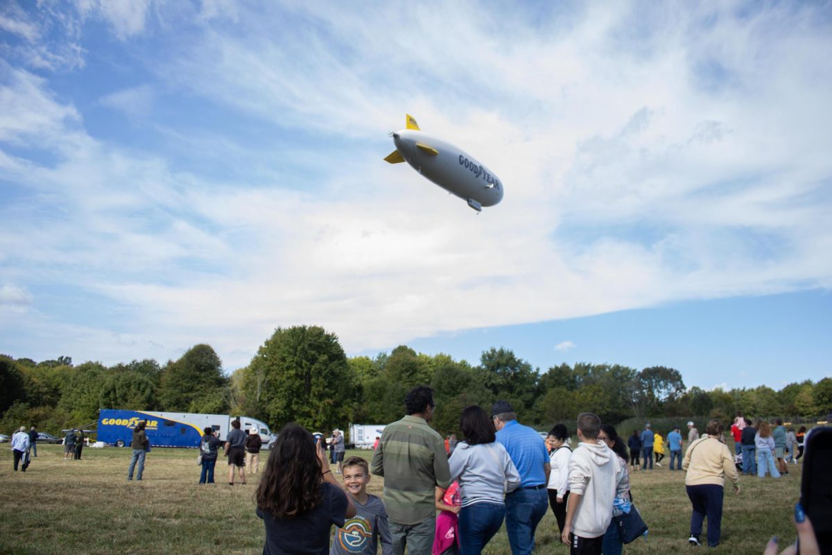 Attendees of the Aeronautics and Engineering Expo watches the Goodyear Blimp in the air on Saturday, Sept 6, 2025.
