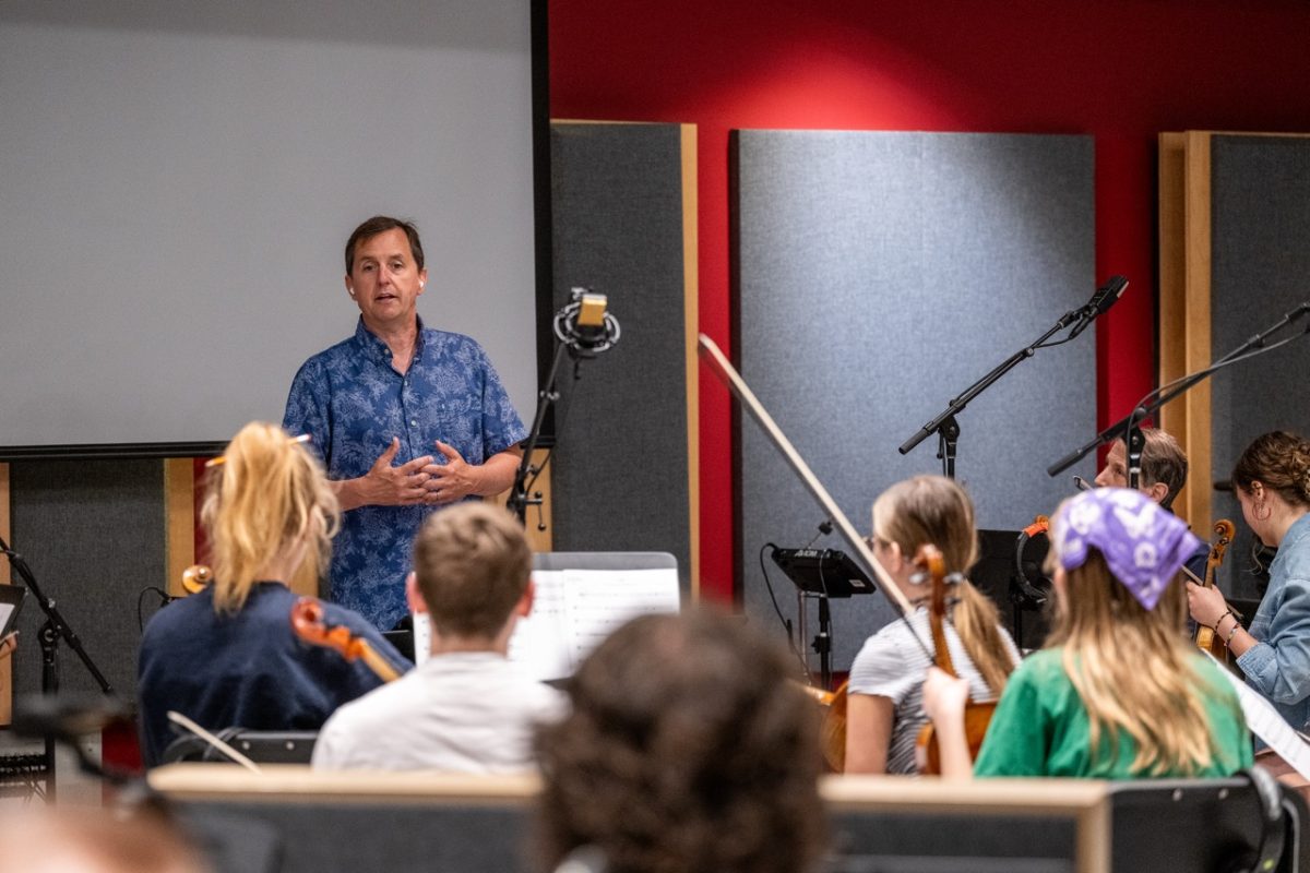 Scott Hallgren, an associate professor in the School of Media and Journalism, talks to students before they record orchestrations for the short film "Photography."