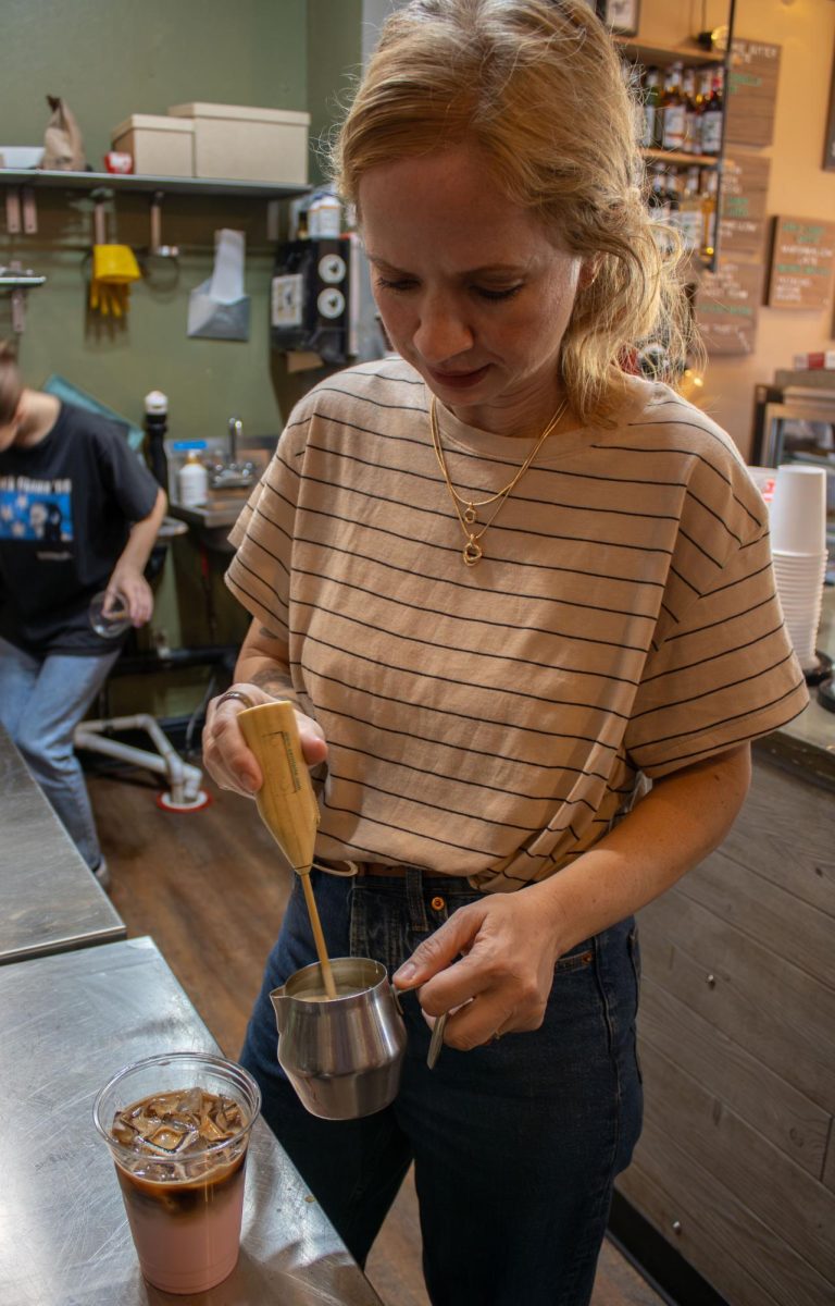 Scribbles Coffee manager, Beth Budzar stirs the cold foam to top off the HER latte on Saturday, Oct. 18, 2025. The HER latte has a wild raspberry taste with pink sweet foam on top. 