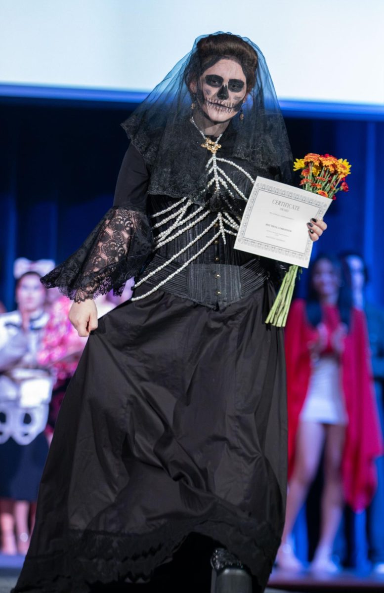 Renie Booth holds her dress as she walks down the runway after winning "Best Visual Composition" during the Modista X Phi Delta Epsilon Fashion Show on Saturday, Oct. 18, 2025.