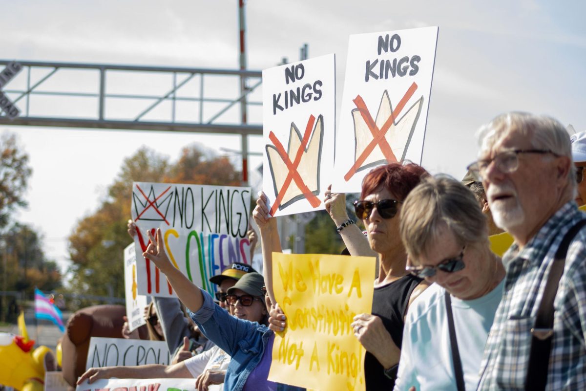 Demonstrators hold up their signs on the side of South Water Street during the No Kings Protest on Saturday, Oct. 18, 2025. 
