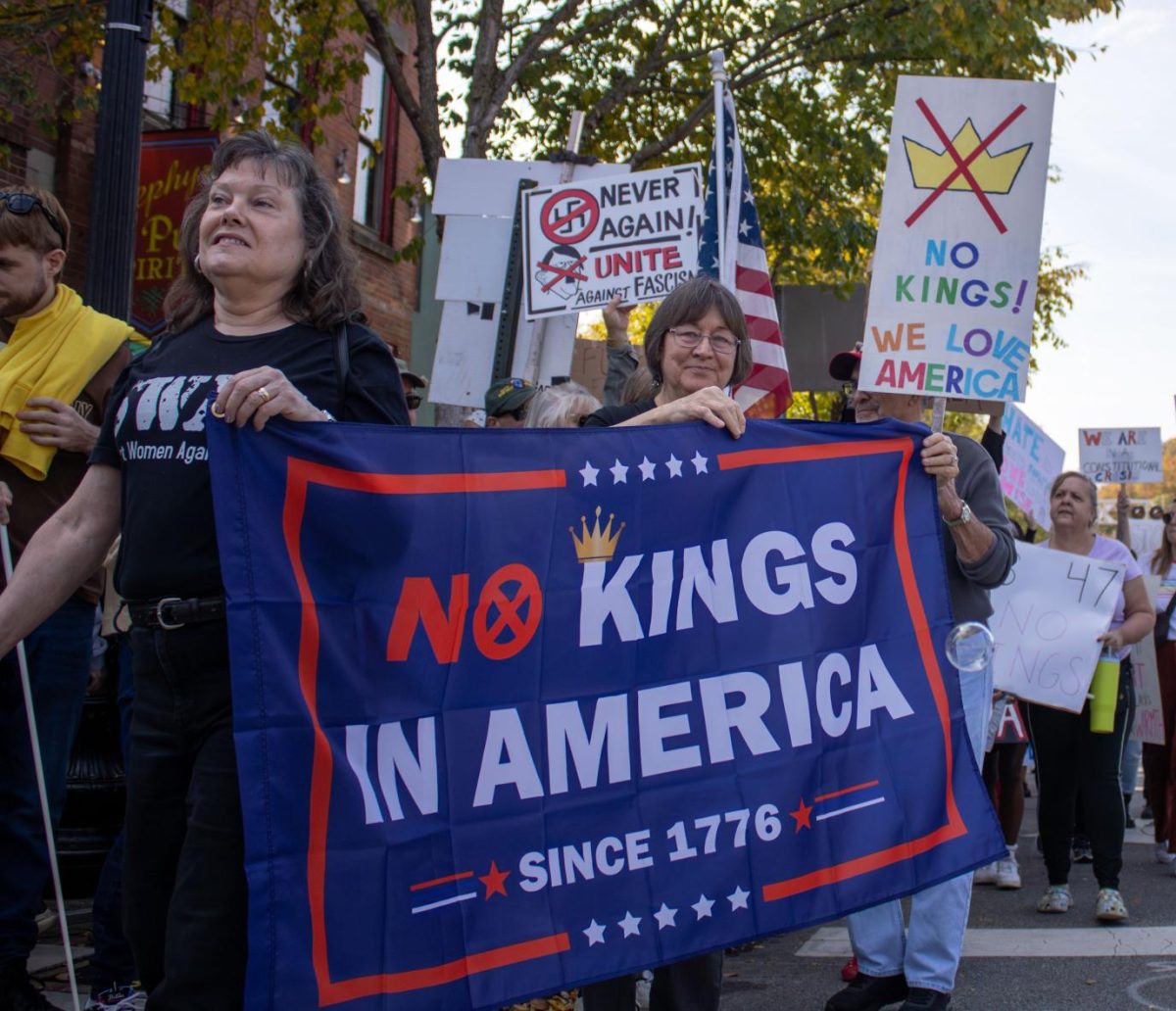 Protesters hold signs and flags as they march on the street during the No Kings protest on Saturday, Oct. 18, 2025.