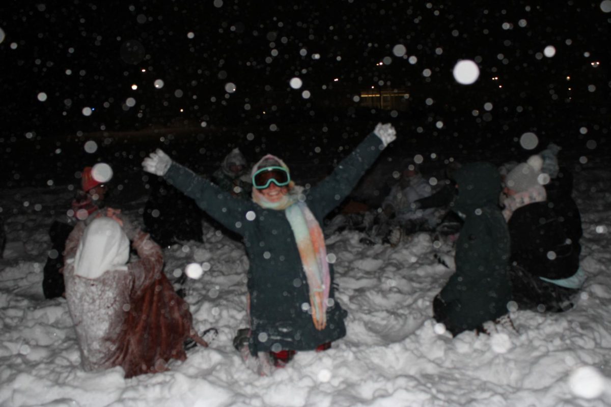 Junior exercise science major, Ava  throws her hands up while sitting in a circle with other students at the snowball fight at Taylor Hall on Sunday, Jan. 25, 2026.