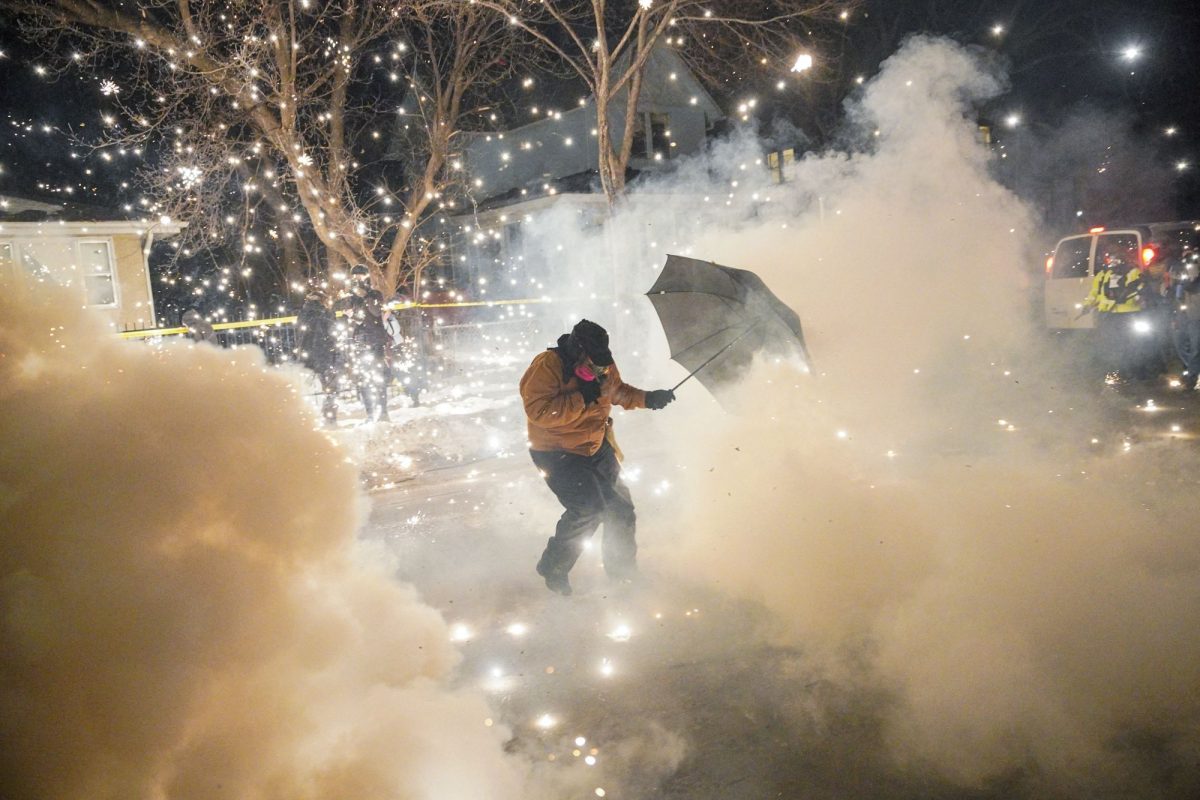 A protester attempts to protect themselves as federal agents fire flash-bangs and pepper balls, amid risingstensions after federal law enforcement agents were involved in another shooting incident, a week after an ICE agent fatally shot Renee Nicole Good, in north Minneapolis, Minnesota, on January 14, 2026.