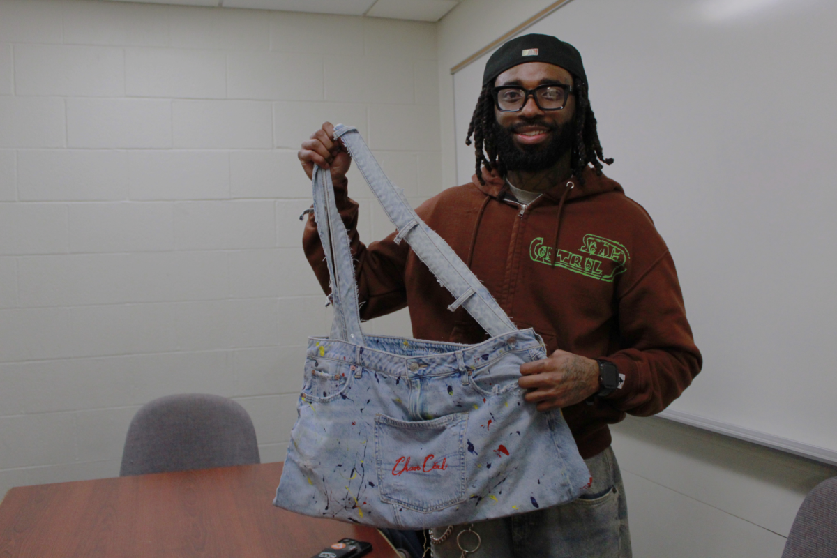 Zane Cylar, a junior fashion design major, is the founder of Chaos Control. He is holding an upcycled bag made from denim material on Feb. 4, 2026.
