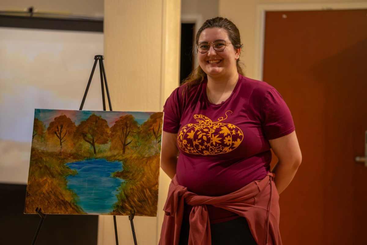 Junior biology major Lia Swimeheart displays her painting at Bob Ross Paint Night in Oscar Ritchie Hall on March 5, 2026.