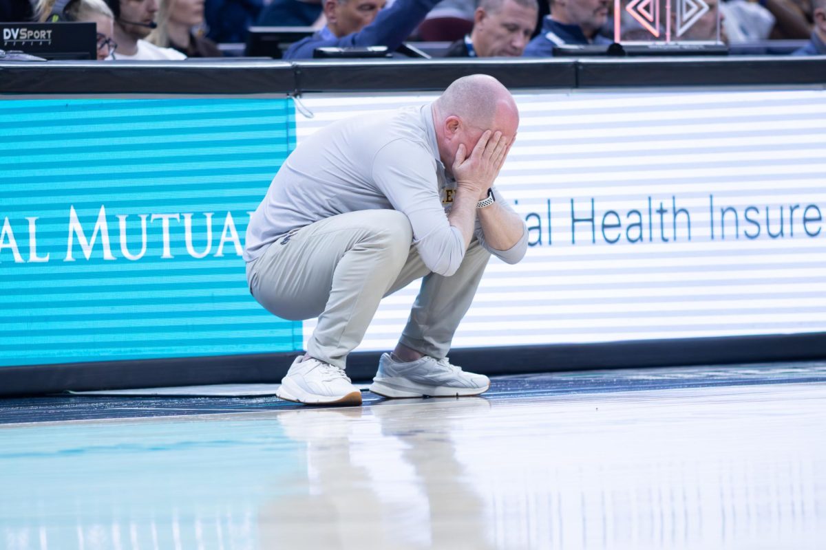 Kent head coach Rob Senderoff crouches after a foul call on Kent junior Cian Medley in the second half of the Semifinal round against the University of Akron on March 13, 2026. 